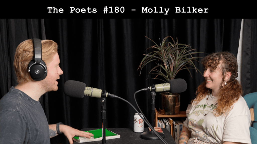 A man and a woman engaged in conversation during a podcast recording, with microphones in front of them. The background features black curtains and a plant. The woman is wearing a t-shirt with a design, and there is a can of soda on the table.